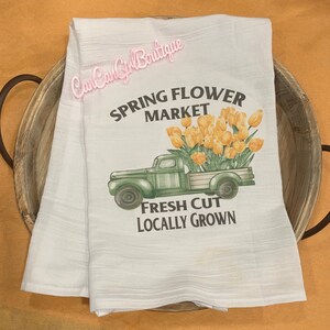Puede incluir: Toalla de cocina blanca con un cami&oacute;n vintage verde que lleva un ramo de tulipanes amarillos. El texto dice "Spring Flower Market" y "Fresh Cut Locally Grown".