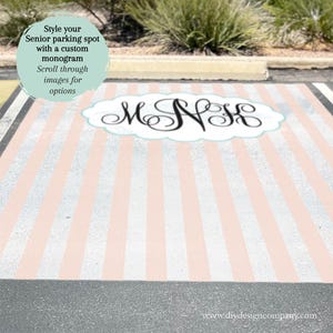 May include: A parking spot painted with vertical light pink and white stripes. Centered is a white cloud-shaped emblem containing a black cursive monogram with the letters M, N, and K. Text overlay reads: Style your Senior parking spot with a custom monogram. Scroll through images for options.