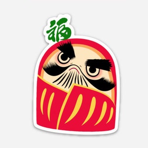 May include: A red and yellow daruma doll with a black mustache and eyebrows. The doll has large, black eyes and a serious expression. The word "福" (meaning "good fortune") is written in green on the doll's head.