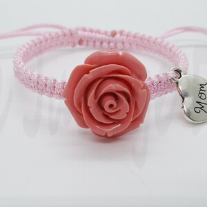 May include: Pink braided bracelet with a coral rose charm and a silver heart charm that says "Mom".