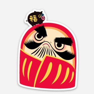 May include: A red and yellow Daruma doll with a black mustache and eyebrows. The doll has a small black pig with the Chinese character for "good fortune" on its head.