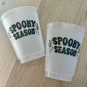 May include: Two white plastic cups with black text that reads "Spooky Season" and a skeleton graphic.