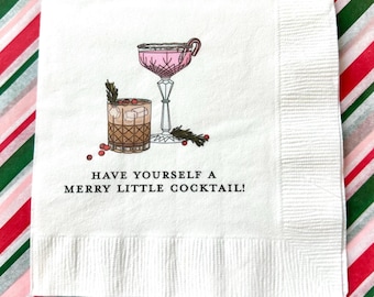 May include: White paper cocktail napkin with a pink and brown cocktail illustration and the text "Have yourself a merry little cocktail!"