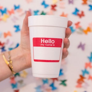 May include: A white foam cup with a red name tag that says "Hello my name is" on a white background with colorful butterfly confetti.