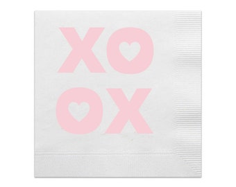 Puede incluir: Servilleta de papel blanca con el texto "XO XO" en rosa claro. Las letras "O" tienen cada una un símbolo de corazón. La servilleta tiene un borde texturizado y plegado en el lado derecho.