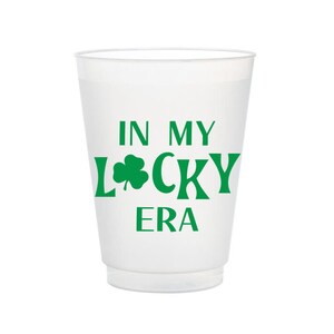 May include: White plastic cup with green shamrock and text "In My Lucky Era".