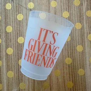 May include: A white plastic cup with the text "IT'S GIVING FRIENDS" printed in orange.