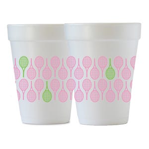 May include: Two white foam cups with a repeating pattern of pink and green tennis rackets. The cups are cylindrical with a slightly flared top. The tennis racket design is a decorative element.