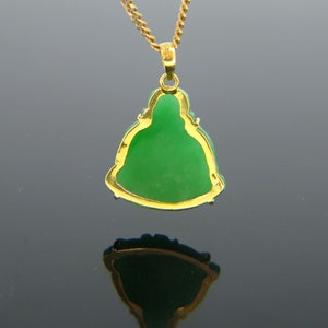 May include: A gold pendant necklace featuring a green jade Buddha figurine. The pendant is detailed with gold trim and the Buddha is sitting in a meditative pose.