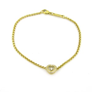 May include: A gold chain bracelet with a heart-shaped pendant featuring a single diamond in the center and smaller diamonds around the edge.