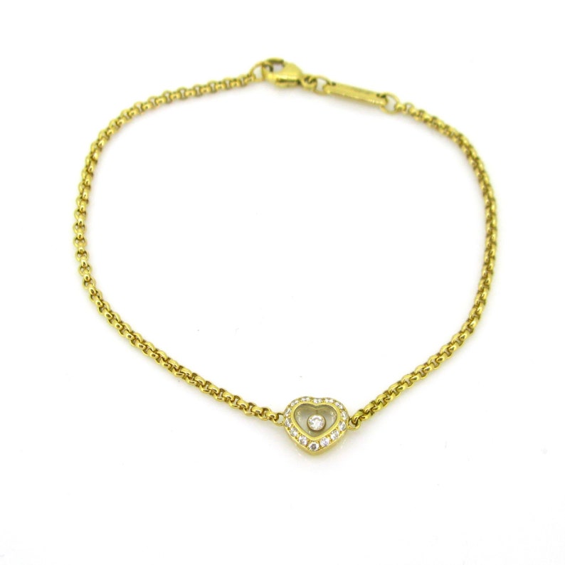 May include: A gold chain bracelet with a heart-shaped pendant featuring a single diamond in the center and smaller diamonds around the edge.