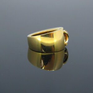 May include: A gold ring with a single diamond set in a curved band.