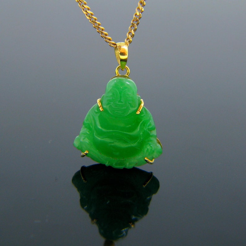 May include: A green jade pendant of a smiling Buddha figure, set in gold, hanging from a gold chain.