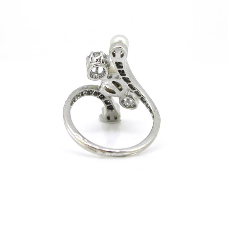 May include: A silver ring with a pearl and clear stones set in a delicate, swirling design.