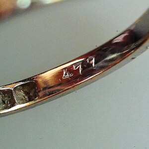 May include: Close-up of a gold band with the number "471" engraved on the inside.