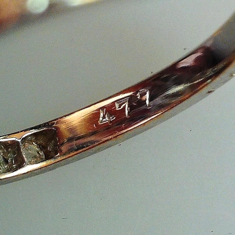 May include: Close-up of a gold band with the number "471" engraved on the inside.