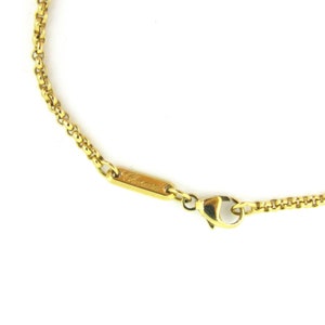 May include: A gold chain necklace with a lobster clasp closure. The chain is made of small, round links. The necklace has a small tag with the word "Chopard" engraved on it.