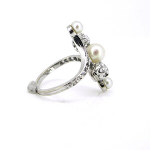 May include: A silver ring with a curved band set with pearls and diamonds.