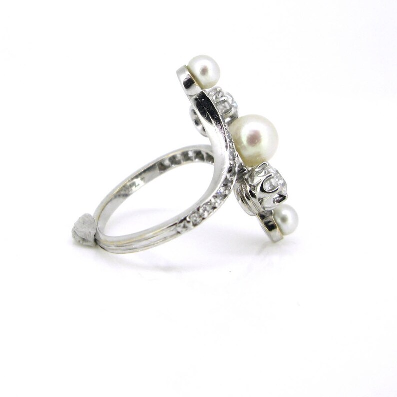 May include: A silver ring with a curved band set with pearls and diamonds.