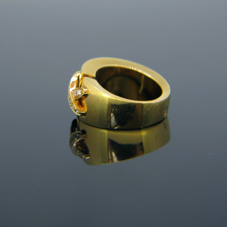 May include: A gold ring with a diamond accent. The ring is open and has a smooth, polished finish.