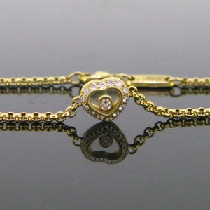 May include: A gold chain bracelet with a heart-shaped pendant featuring a floating diamond. The pendant is set with smaller diamonds around the edge.