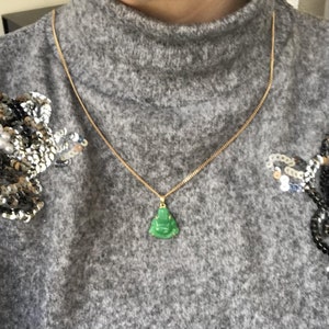 May include: A gold chain necklace with a green jade Buddha pendant.