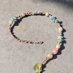 May include: A handmade macrame bracelet featuring a variety of beads in shades of blue, pink, and cream. The bracelet includes a gold starfish charm and is displayed on a gray surface.