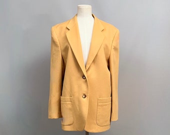May include: A yellow blazer with two button closures and two patch pockets. The blazer is on a mannequin against a gray background.