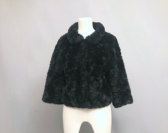May include: A black faux fur jacket with a collar and long sleeves. The jacket is on a white mannequin.