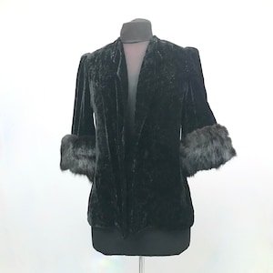 May include: A black velvet jacket with fur trim on the cuffs. The jacket has a shawl collar and a relaxed fit.