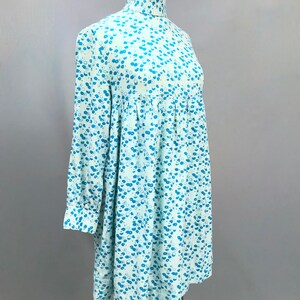 May include: A light blue dress with a high neck and long sleeves. The dress has a small blue floral pattern.