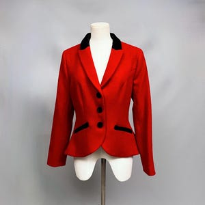 Op de afbeelding: Een rode blazer met een zwarte fluwelen kraag en bies. De blazer heeft een aansluitende pasvorm en vier knopen.