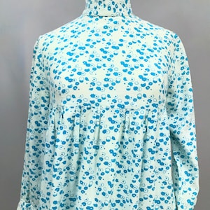 May include: A light blue dress with a high neck and long sleeves. The dress has a small blue floral pattern.