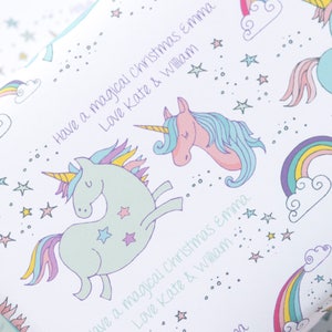 May include: White wrapping paper with a repeating pattern of rainbows, stars, and unicorns. The text "Have a magical Christmas Emma Love Kate & William" is printed on the paper.