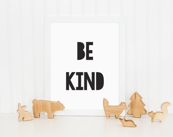 May include: A white framed print with the text "BE KIND" in black letters, surrounded by wooden animal figurines on a white surface.