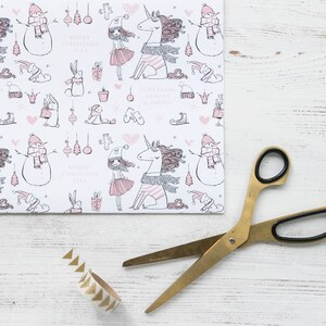 May include: White wrapping paper with a pink and black repeating pattern of a unicorn, a girl, a snowman, and a bunny. The text "Merry Christmas Ella" and "Love from Mummy & Daddy" is printed on the paper.