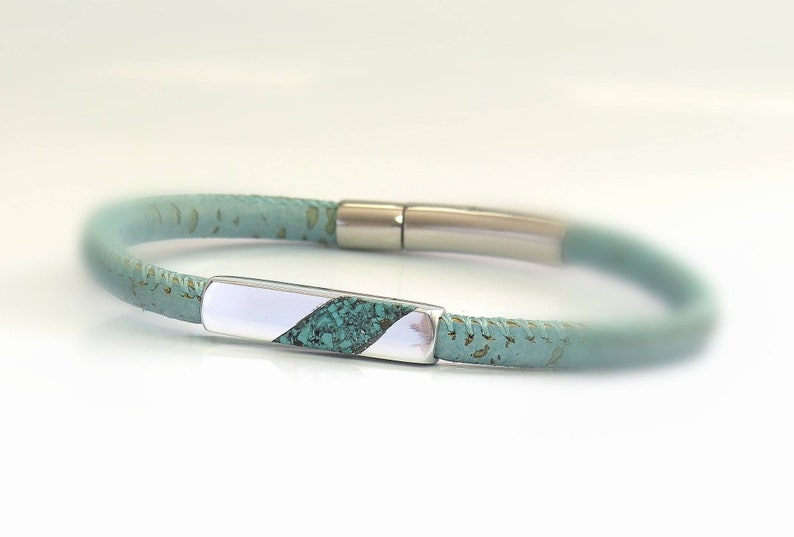 Peut inclure: Un bracelet en cuir turquoise avec un fermoir en argent en forme de barre. La barre est incrust&eacute;e de turquoise.