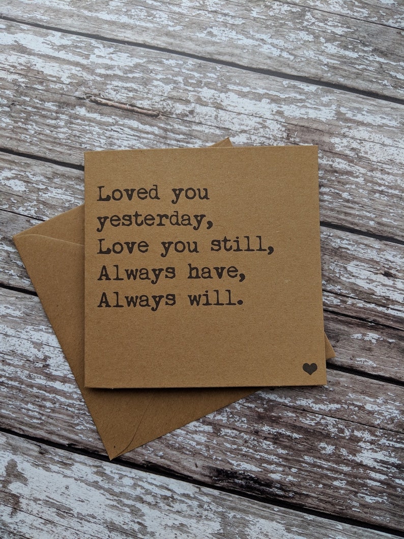Puede incluir: Una tarjeta marr&oacute;n con el texto "Loved you yesterday, Love you still, Always have, Always will." impreso en negro. Un peque&ntilde;o coraz&oacute;n negro est&aacute; impreso en la esquina inferior derecha.
