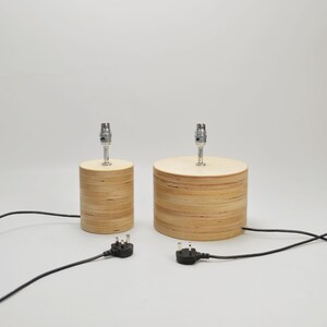 Puede incluir: Dos l&aacute;mparas de mesa de madera con cables y enchufes negros. Las l&aacute;mparas son de madera marr&oacute;n claro y tienen un dise&ntilde;o sencillo.