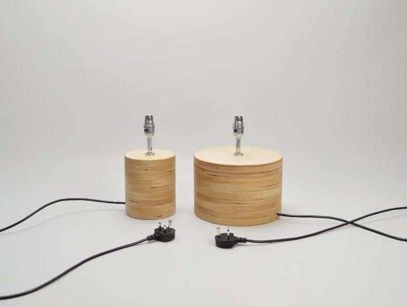 Puede incluir: Dos l&aacute;mparas de mesa de madera con cables y enchufes negros. Las l&aacute;mparas son de madera marr&oacute;n claro y tienen un dise&ntilde;o sencillo.