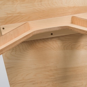 May include: The underside of a wooden table with a light wood finish. The table legs are made of plywood and are attached to the table top with screws.