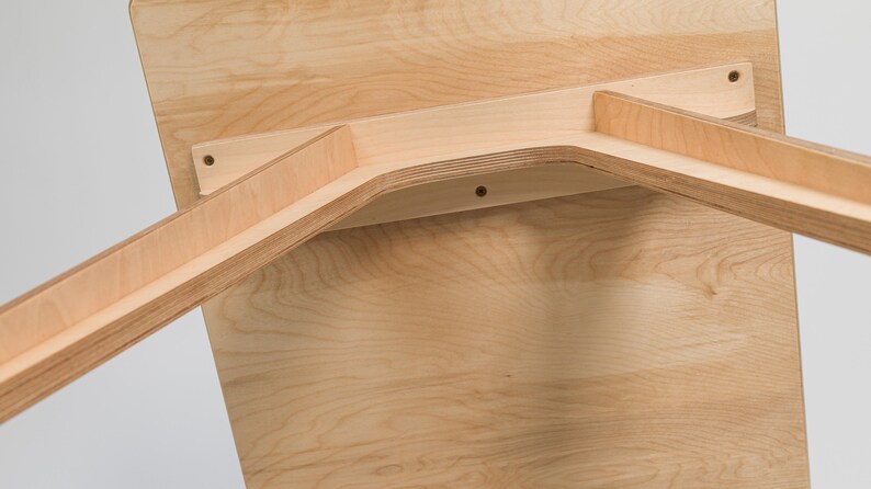 May include: The underside of a wooden table with a light wood finish. The table legs are made of plywood and are attached to the table top with screws.