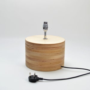 Puede incluir: Una l&aacute;mpara de mesa de madera con un acabado de madera natural y una toma de l&aacute;mpara cromada. La l&aacute;mpara tiene un cable el&eacute;ctrico negro con un enchufe est&aacute;ndar.
