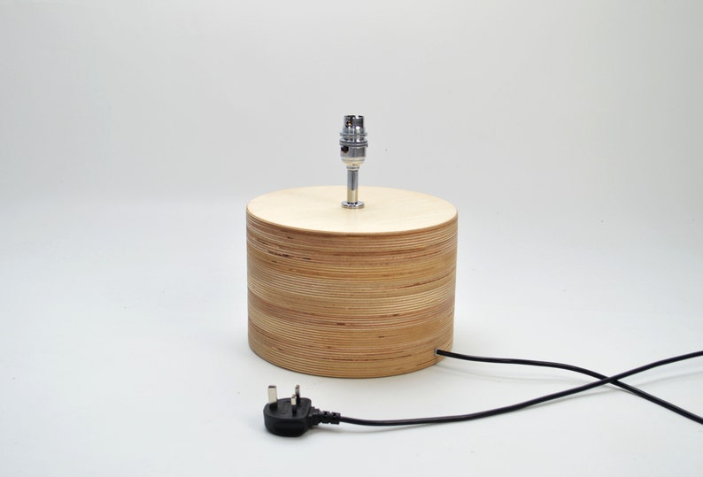 Puede incluir: Una l&aacute;mpara de mesa de madera con un acabado de madera natural y una toma de l&aacute;mpara cromada. La l&aacute;mpara tiene un cable el&eacute;ctrico negro con un enchufe est&aacute;ndar.