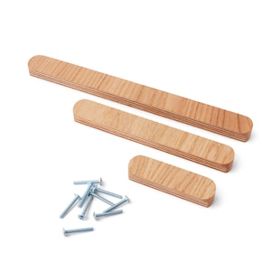 May include: Three wooden cabinet pulls of different lengths, with rounded ends, and a pile of silver screws. The pulls are made of light-coloured wood with a visible grain. The hardware is set against a white background.