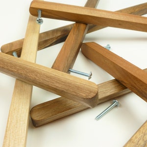 Könnte beinhalten: Nahaufnahme von vier Holzknaufgriffen mit silbernen Schrauben. Die Griffe sind unbehandelt und haben eine natürliche Holzmaserung.