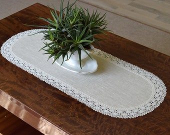 Puede incluir: Un camino de mesa ovalado blanco con un delicado borde de encaje. El camino de mesa está hecho de lino y es perfecto para agregar un toque de elegancia a cualquier mesa.