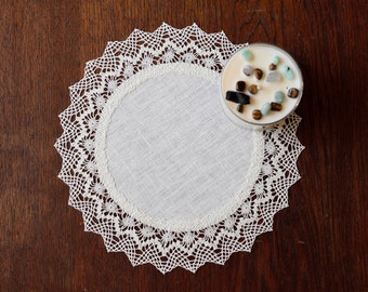 May include: A white crocheted doily with a clear glass candle holder filled with small stones and crystals.
