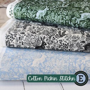 May include: Three stacked fabric rolls with nature-themed patterns. The top roll features a dark green design with white rabbits and foliage. The middle roll has a black and white illustration of rabbits and flowers. The bottom roll is light blue with white rabbits and floral elements. The text "Cotton Pickin Stitchn" is visible.