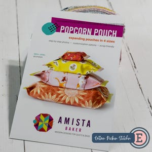 May include: A pattern for a "Popcorn Pouch" with step-by-step photos and customization options. The image shows four fabric pouches in different sizes and floral patterns. The skill level is beginner. The brand name is Amista Baker.